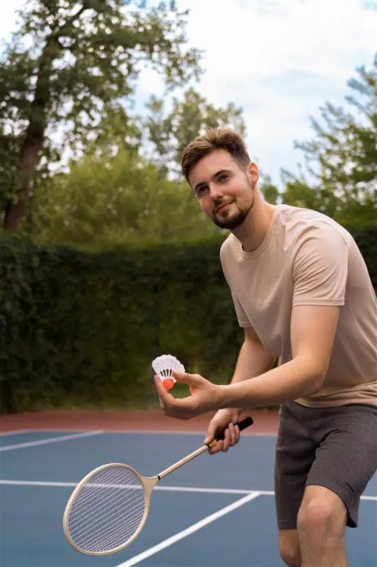 Glad fyr skal til at serve i badminton Credit:https://www.freepik.com/free-photo/smiley-man-playing-badminton-side-view_32408552.htm#&position=19&from_view=collections&uuid=3a1156e1-3521-4807-a3e8-dead166ebea6